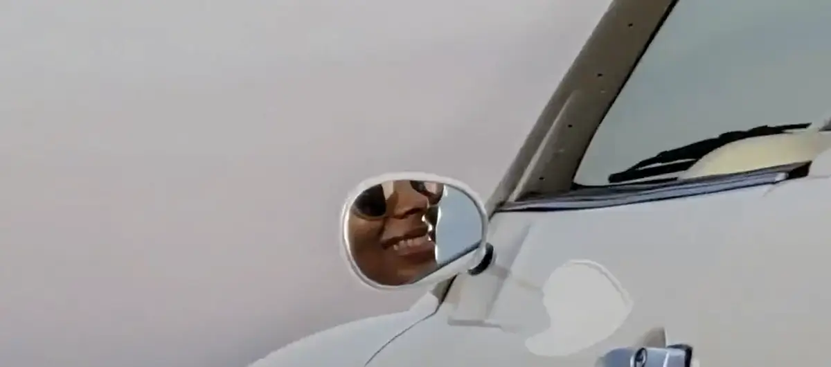 At 10x: the wing mirror and door, a smiling face reflected in the mirror