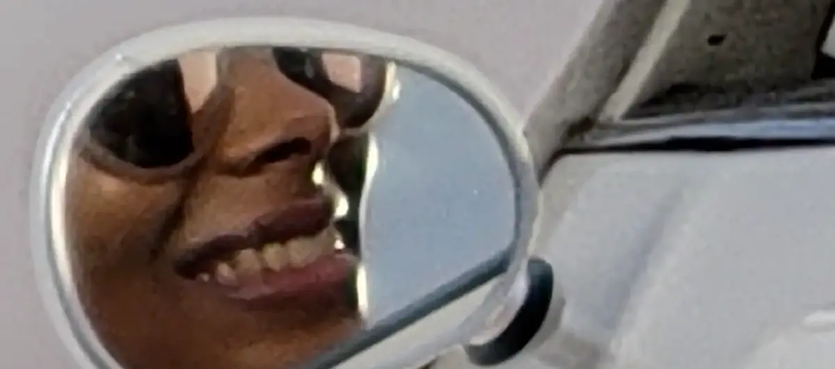 At 30x: the mirror fills the frame, showing a woman's smile and sunglasses