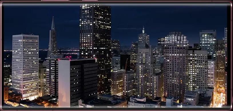 Galaxy S22 Ultra held sideways, a city skyline lit up at night on its screen
