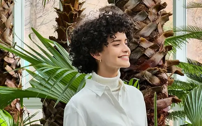 Closer still: the woman's face and shoulders among the leaves