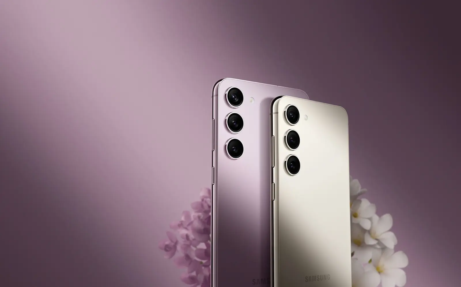 Galaxy S23 series phones in Lavender and Cream, from the back, beside pale flowers