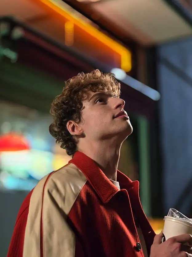 A tight night portrait of the young man looking up, the lights blurred behind him