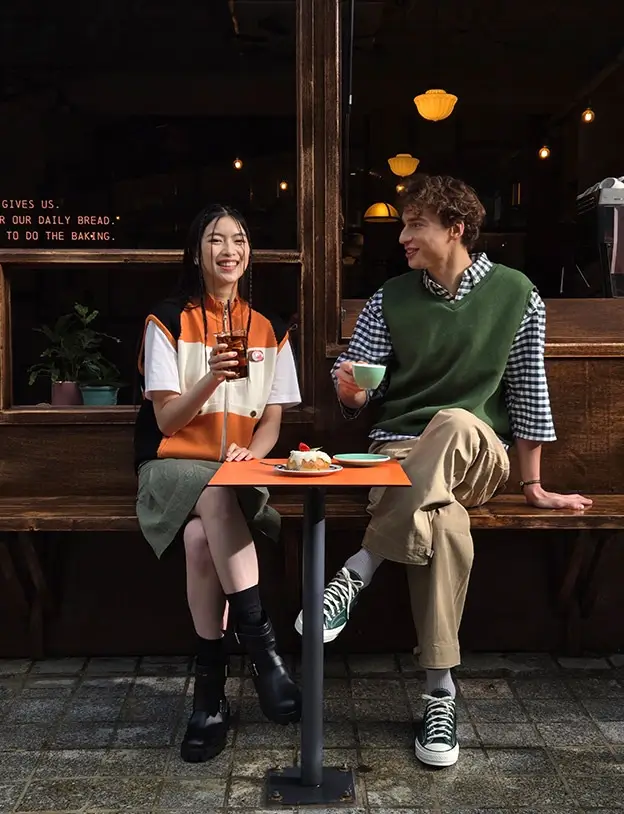Closer: the two friends laughing at the table, one with an iced drink, one with a coffee cup