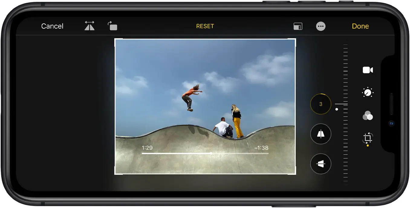 iPhone 11 held sideways, straightening a photo of skateboarders in the Photos editor