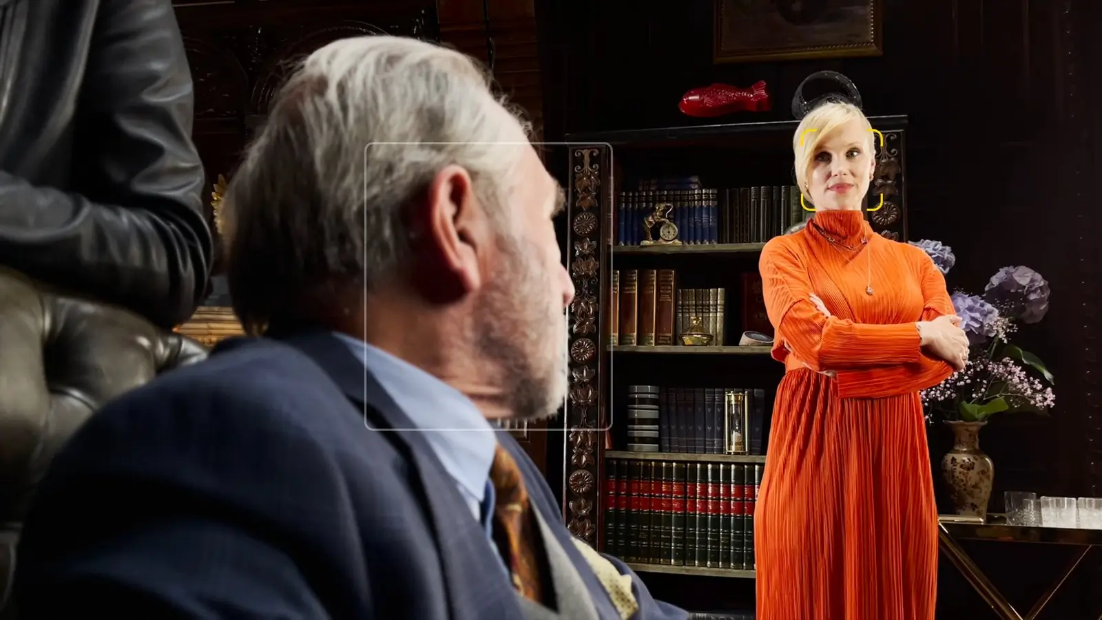 The same shot with the person in front turned and blurred, and the person in the orange dress now in sharp focus