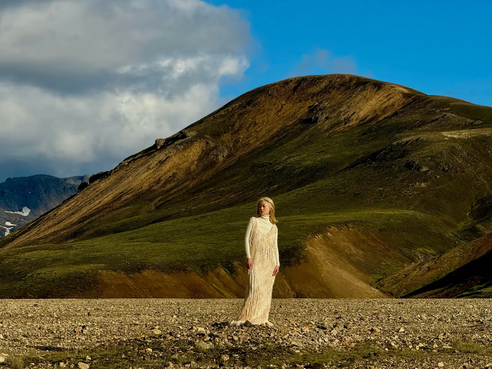 At 120 mm the person in a long cream dress is seen head to toe in front of the hillside