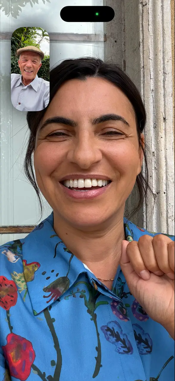 A FaceTime call with the caller smiling in the middle of the frame and the other person in a small window