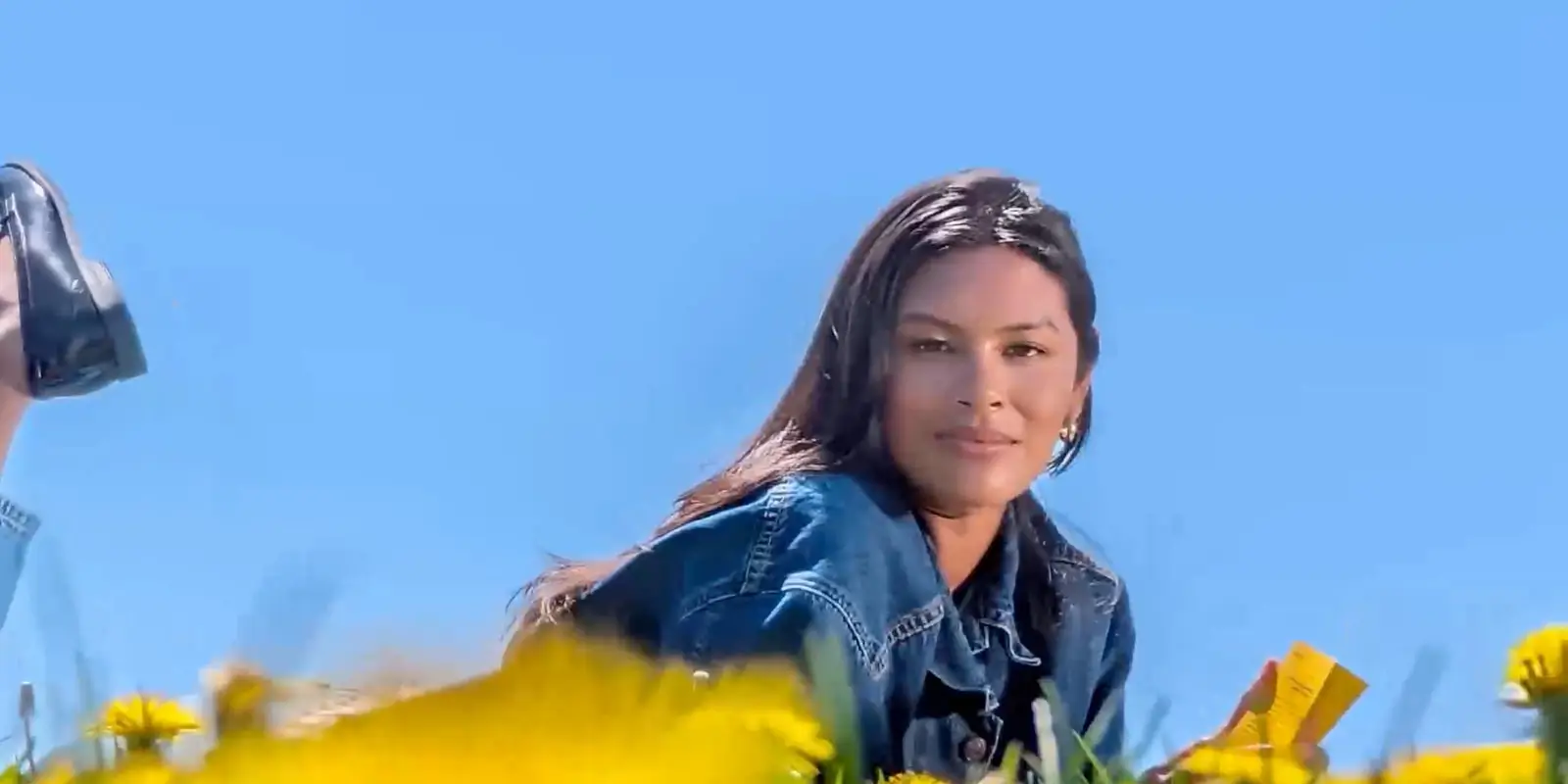 At 20x: the woman's face and denim jacket close up, her shoes in the air behind her