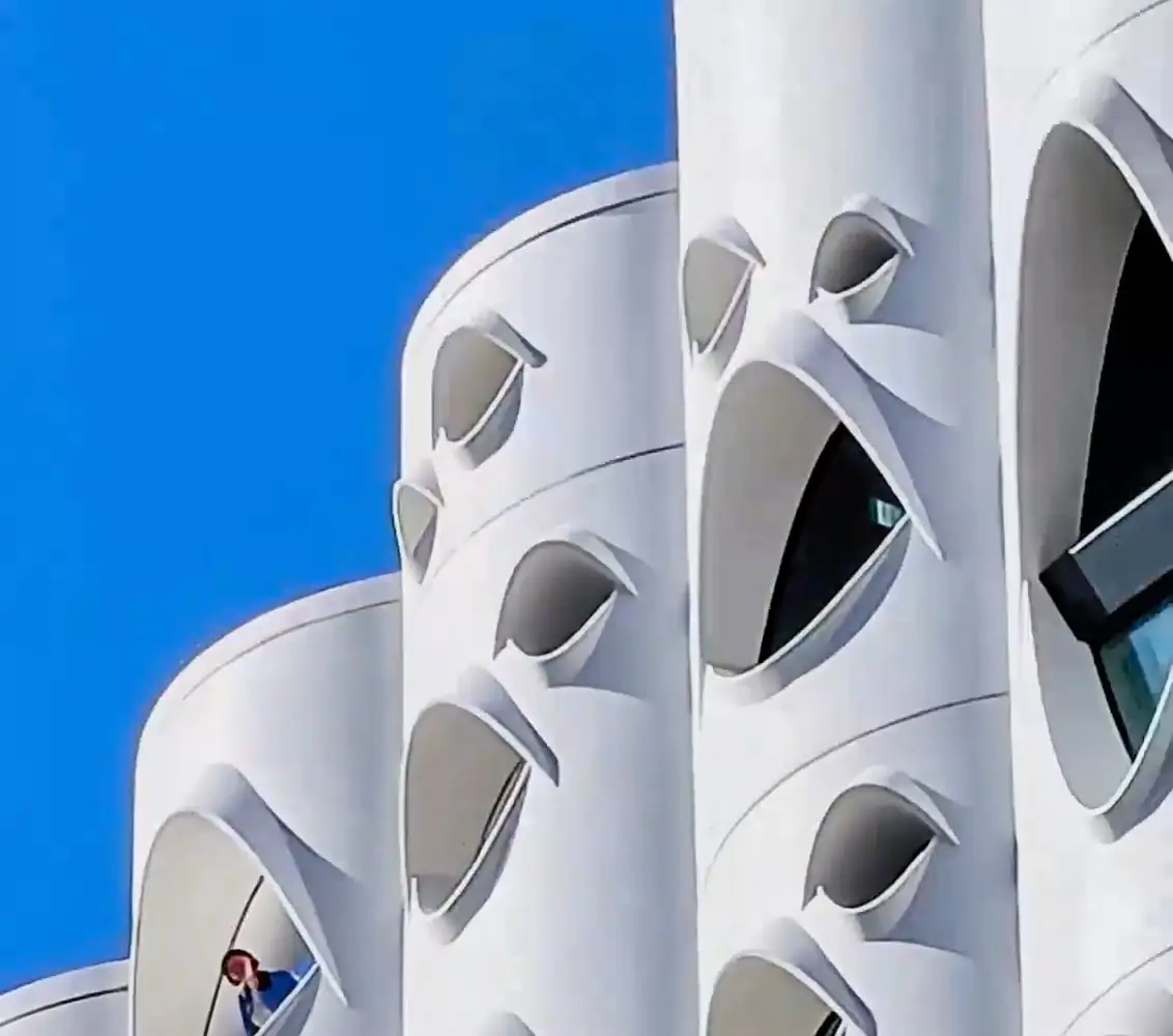 At 10x: two curved balconies, a person small in one of the windows
