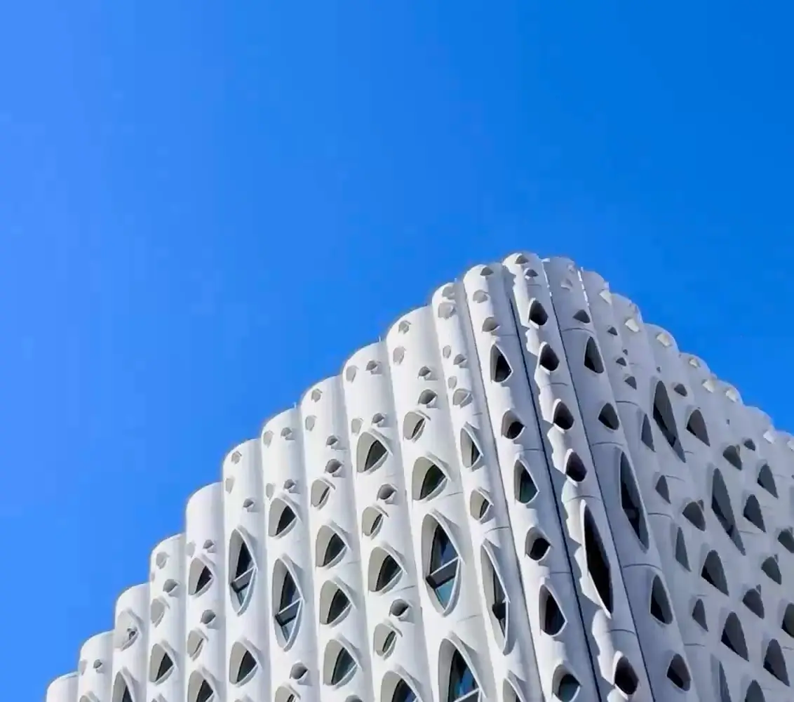At 1x: the same white building corner, larger, under blue sky