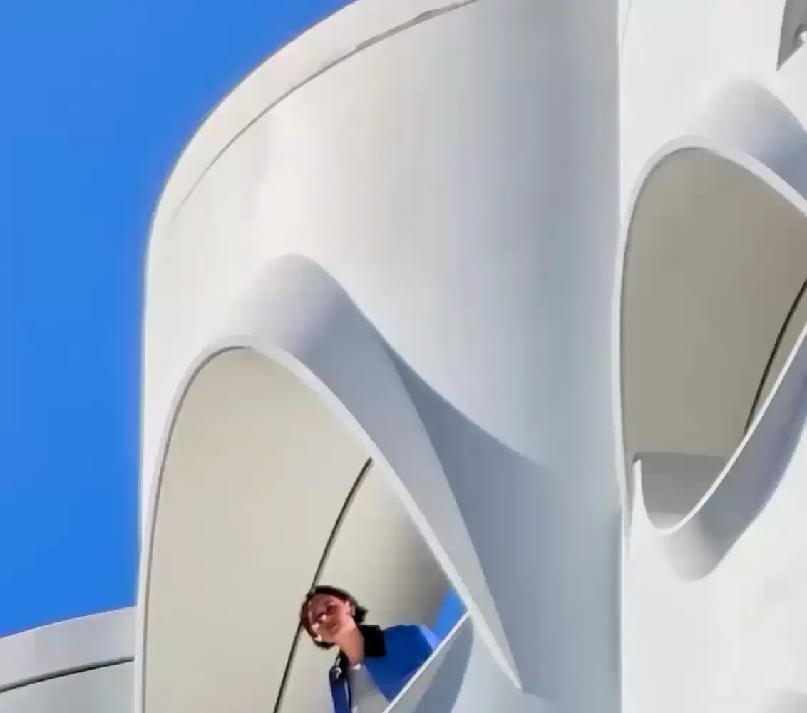 At 20x: a man looks out from one window of the white building