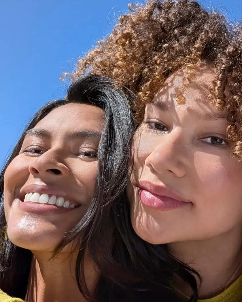 Front camera: two people pose cheek to cheek for a selfie