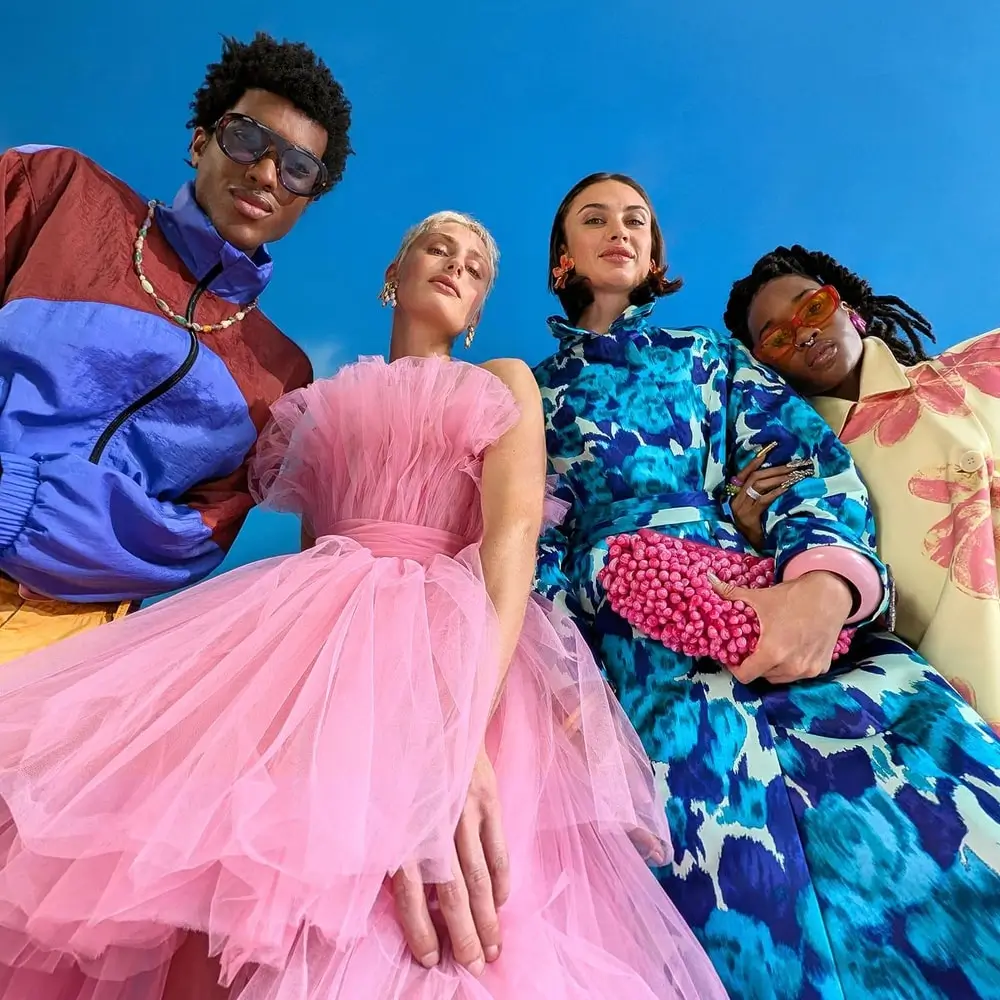 Ultra Wide: a group of four friends in bright outfits shot from a low angle against a blue sky