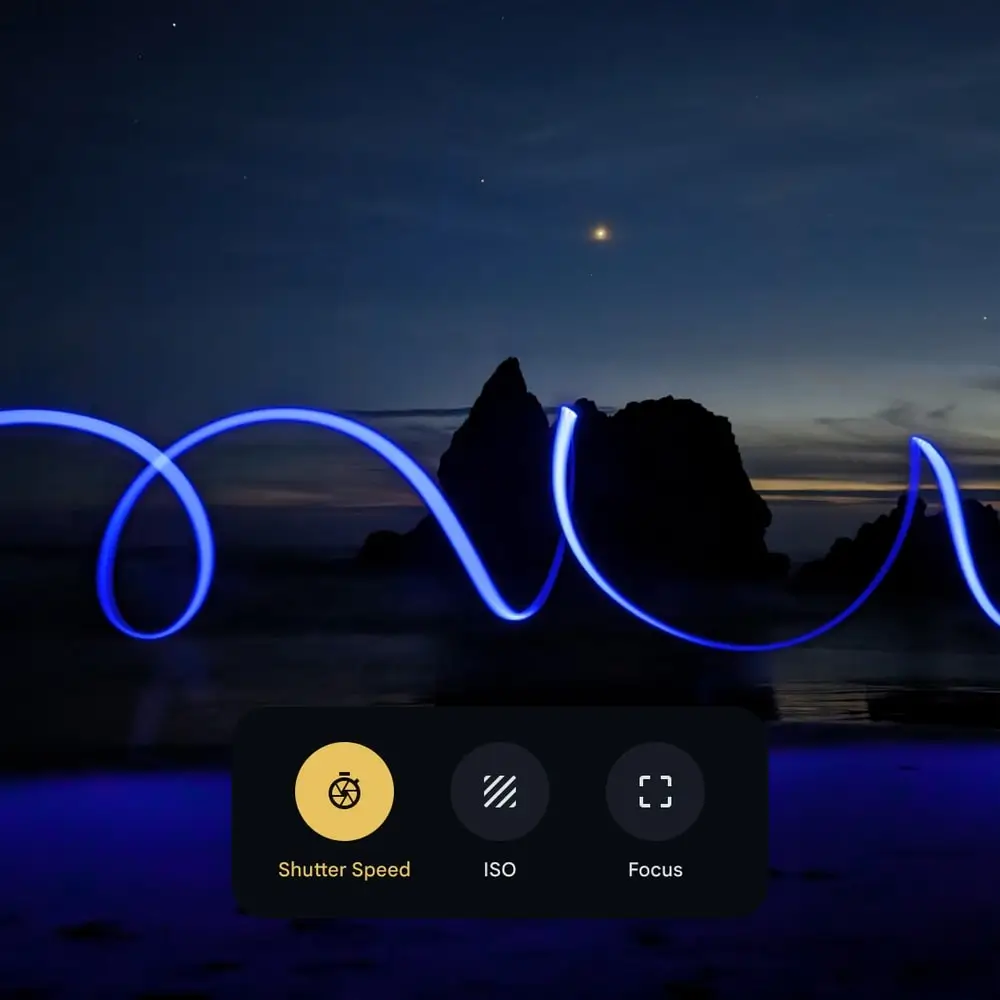 Pro controls: a long exposure of blue light trails over rocks at night, with shutter speed, ISO and focus controls