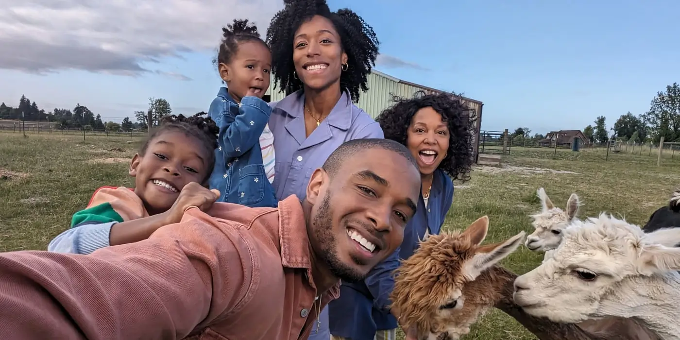 Front camera: a family of five takes a selfie with llamas behind them