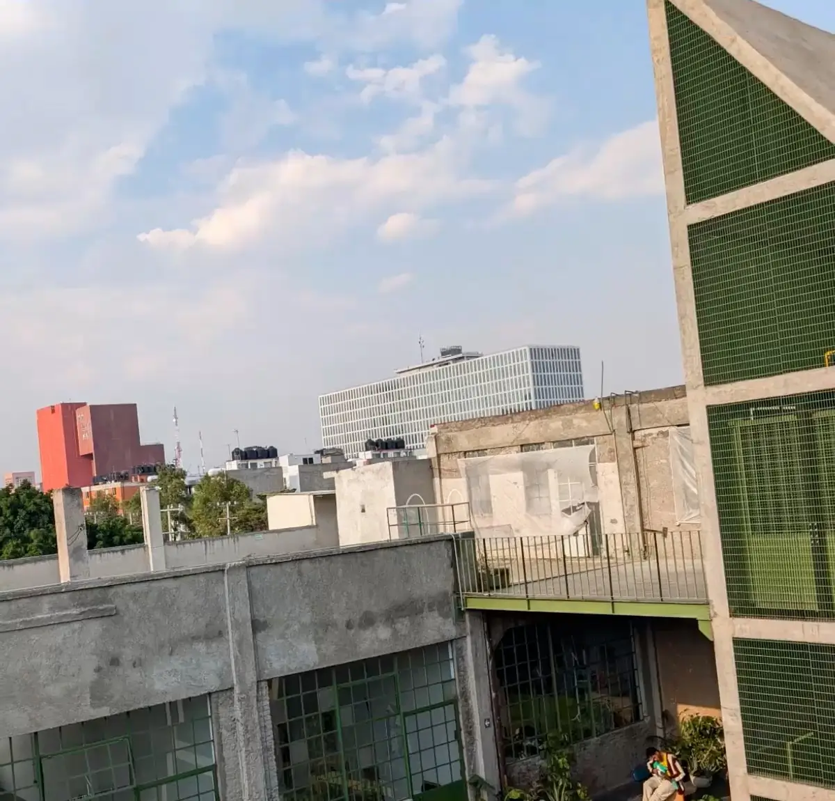 At 1x: the rooftops and skyline, the man still small on the balcony below